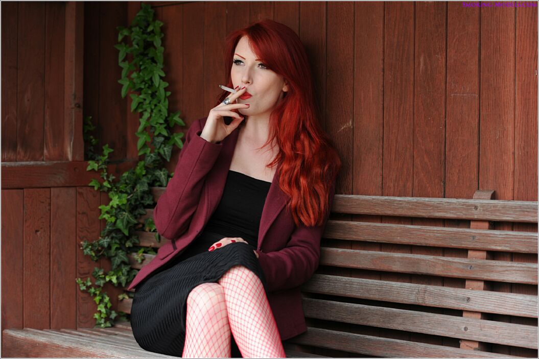 Beautiful red head smokes Marlboro reds at the bus stop wearing fishnets.